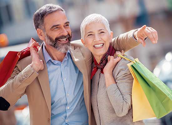A smiling senior couple enjoying a day out shopping, symbolizing the spending habits and financial freedom of retirees during their golden years.