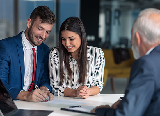 A young couple consults with a financial professional, discussing their retirement planning options.