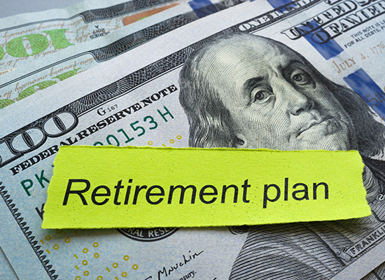 A pile of hundred-dollar bills with a label 'Retirement pla', symbolizing financial savings and 401(k) or IRA withdrawals.