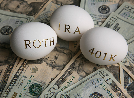 Three eggs labeled 'IRA', 'ROTH', and '401K' resting on a bed of U.S. currency, representing different types of retirement savings accounts.