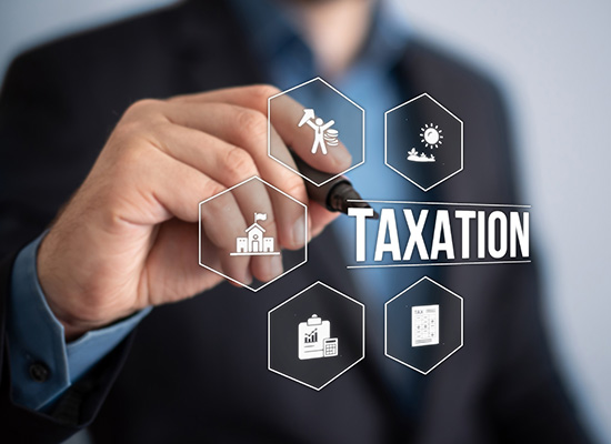 A businessman interacting with a digital display of various icons connected to the word 'TAXATION', symbolizing the complexity of tax systems.