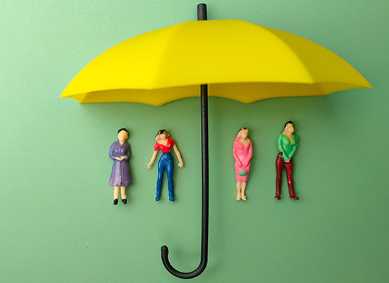 Four miniature figures standing under a yellow umbrella, representing the protection of retirement income through Social Security benefits for those who are retired.