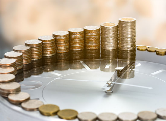 A glass clock face with arranged stacks of coins on it, increasing in height in a clockwise pattern. 