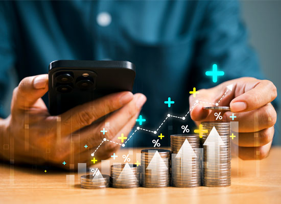 a hand holding aphone with stack of coins insinuating financial growth