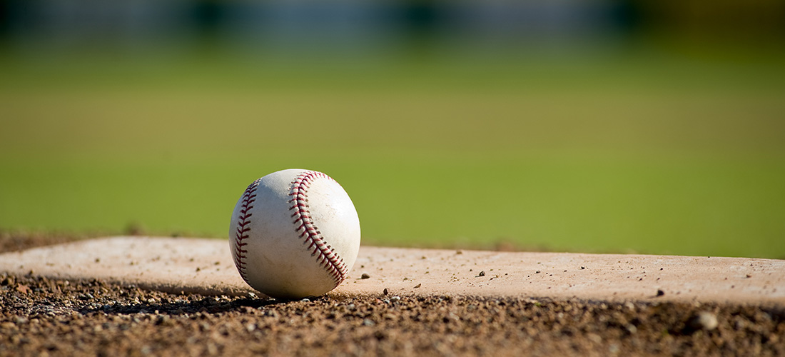 Close up photo of a baseball sitting next to the pitcher's mound