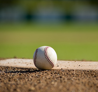 Close up photo of a baseball sitting next to the pitcher's mound
