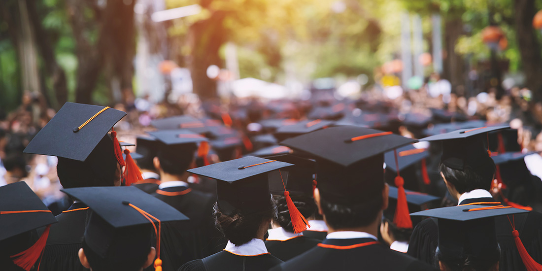 Students with mortarboards and gowns at college graduation