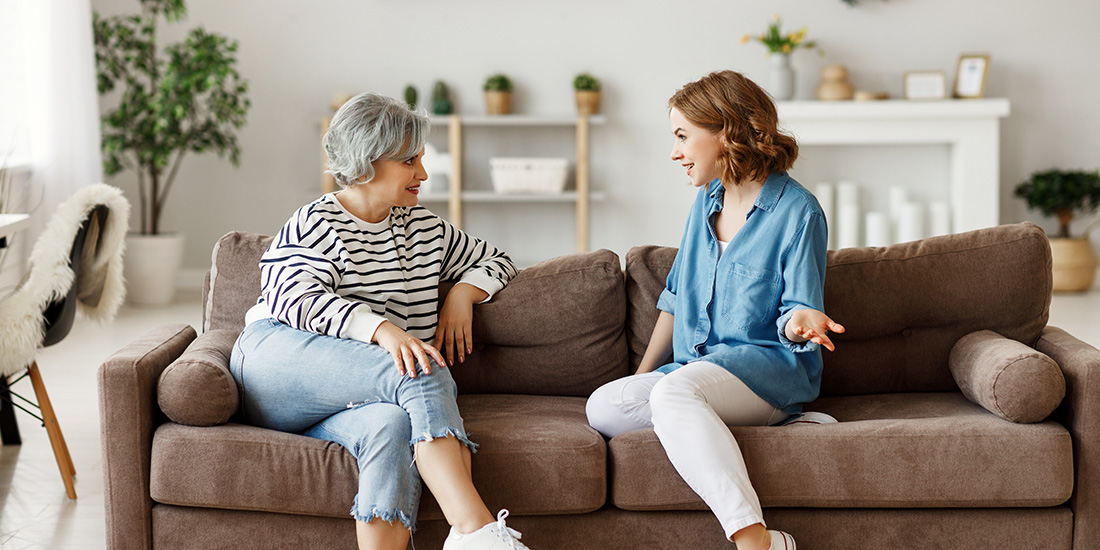 Daughter and aging mother discussing life insurance on couch