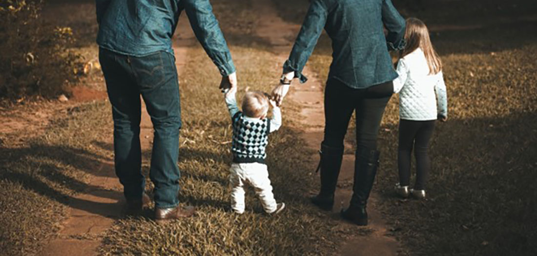 Couple walking hand in hand with their small children