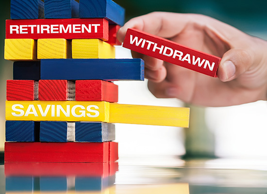 A hand removes a 'WITHDRAWN' block from a stack labeled 'RETIREMENT SAVINGS,' representing the process of accessing retirement funds.