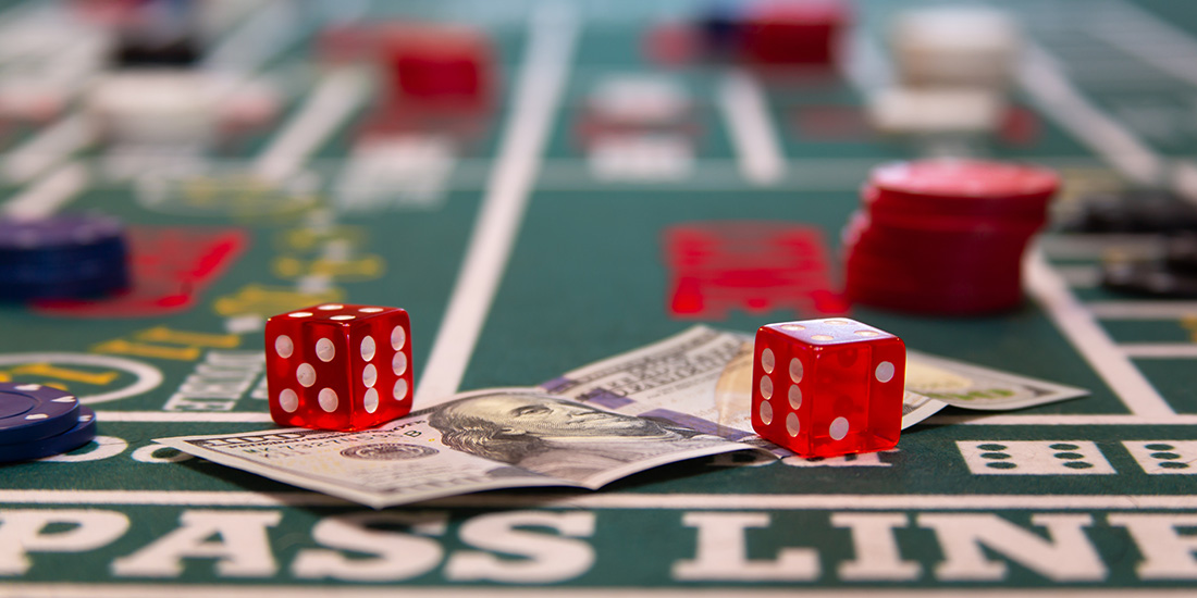 Two red die and hundred dollar bill on craps table