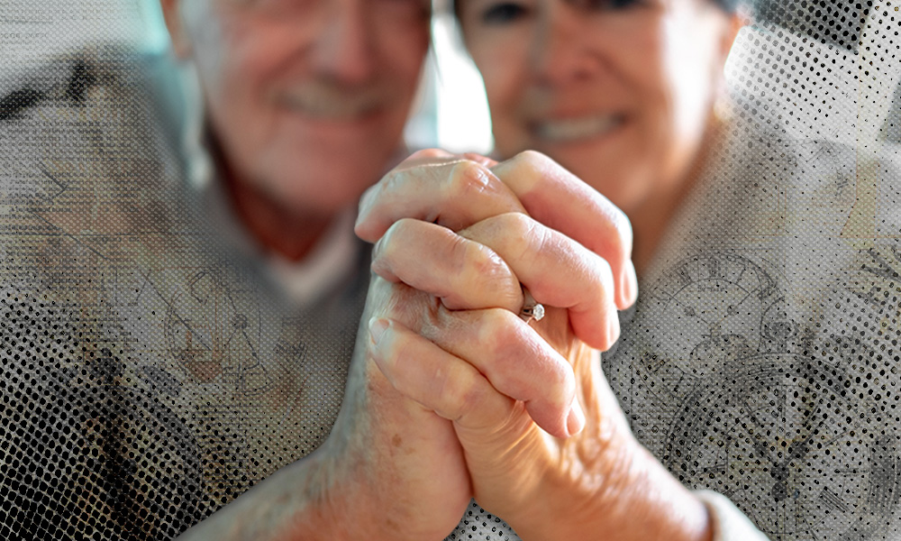 An elderly couple clasping hands, with a focus on a wedding ring