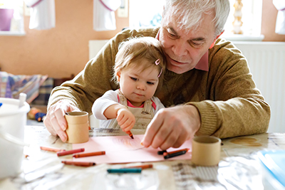 Grandfather drawing with crayons with granddaughter