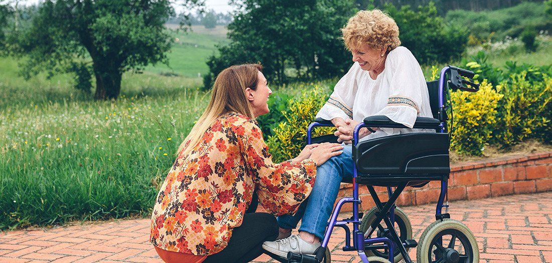 Mother in a wheelchair visiting with her daughter in a garden