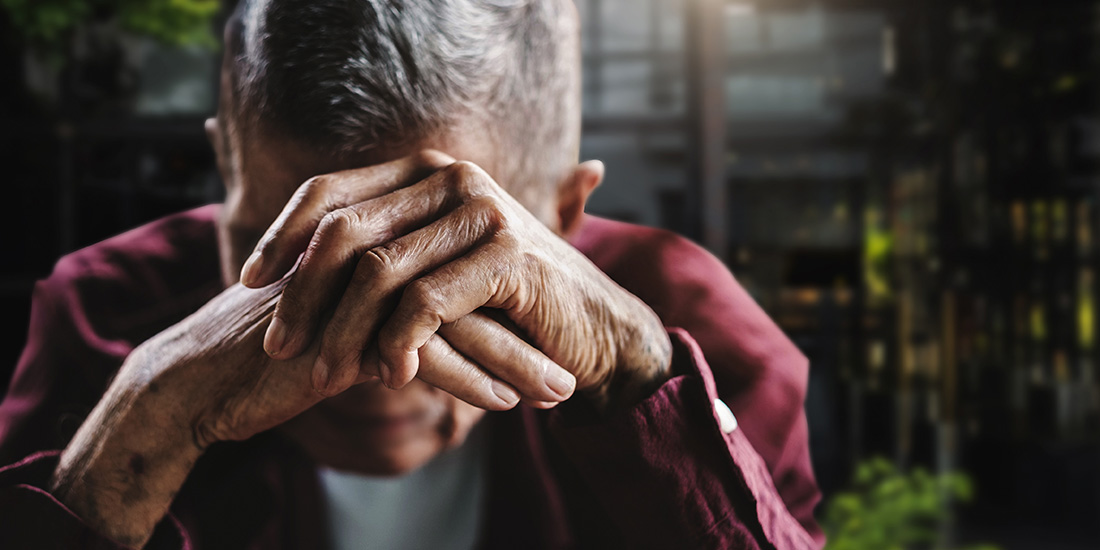Elder man leaning his head against his hands