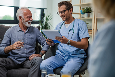 Male nurse speaks with elderly man patient