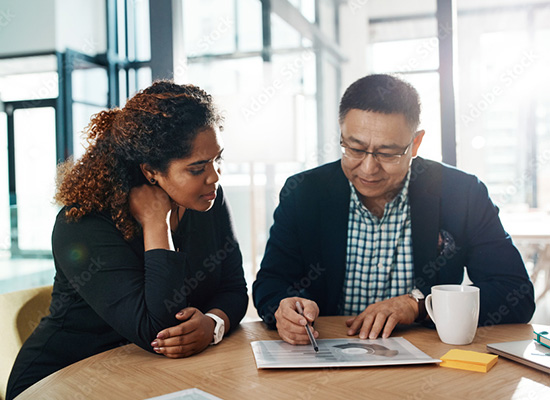 A man and a woman sitting at a table reviewing a document together, symbolizing retirement planning or financial consultation.