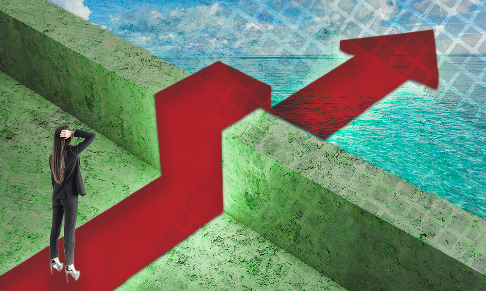 A person stands at the base of a red arrow that navigates over a green barrier, symbolizing the challenge of overcoming psychological biases in financial decision-making.