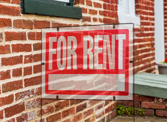 A 'For Rent' sign is displayed outside a brick building