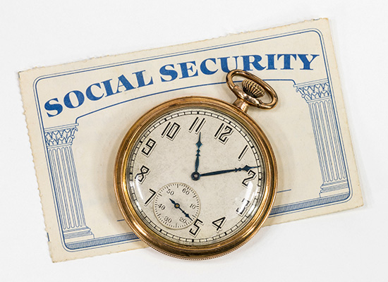 A vintage pocket watch rests on top of a Social Security card, symbolizing the timing and importance of Social Security in retirement planning.