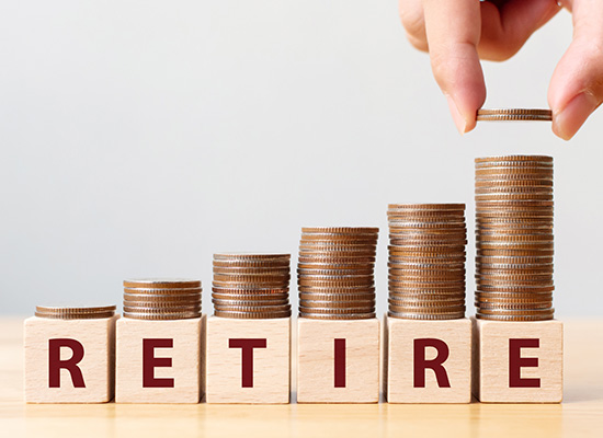 Stacked coins and wooden blocks spelling "RETIRE" illustrate the importance of saving and income planning for a secure retirement.