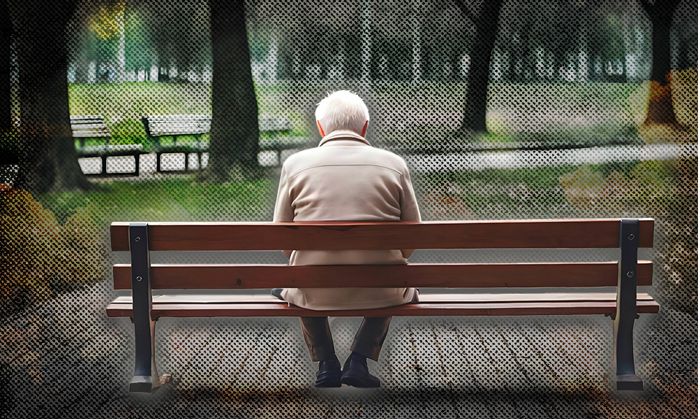 An elderly man sitting alone on a park bench, symbolizing the growing number of Americans aging alone.
