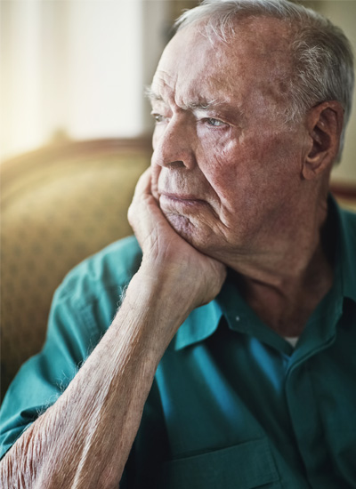 A senior man rests his face in his hand, representing the isolation some older Americans living alone may experience and the need for community connections and informal care networks.