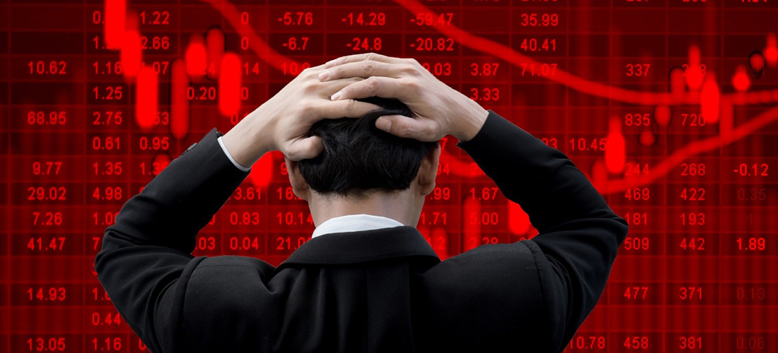 Man holding his head looking at the stock market fall on a computer billboard