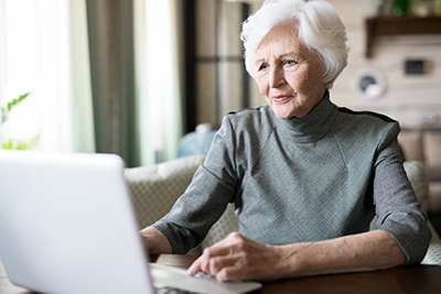 Well dressed rich old woman using laptop