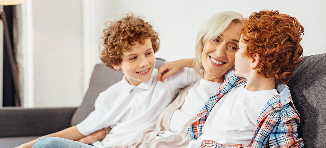 Woman enjoying being a grandmother on the couch with her two ginger grandsons