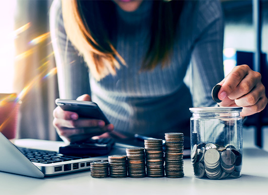 a lady placing coins in a savings jar