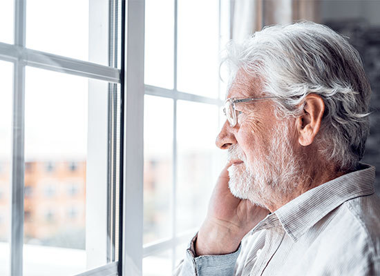 older man on the phone looking out the window