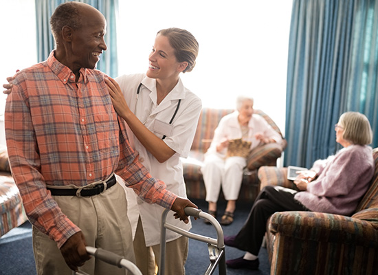 An elderly man receives assistance from a nurse as he uses a walker, highlighting the importance of patient care and support.