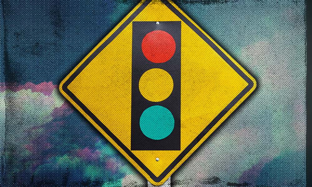A traffic light warning sign against a colorful textured background, symbolizing the three phases of retirement: go-go (green), slow-go (yellow), and no-go (red).