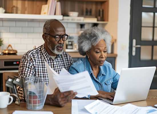 An elderly couple reviewing financial documents together at home, preparing for the three phases of retiremen