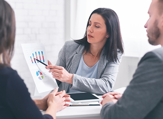 A financial advisor explaining investment charts to a couple, representing the 'go-go' phase of retirement where individuals are active and managing their finances.
