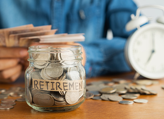 A jar labeled 'Retirement' filled with coins, illustrating the importance of retirement savings and financial planning.