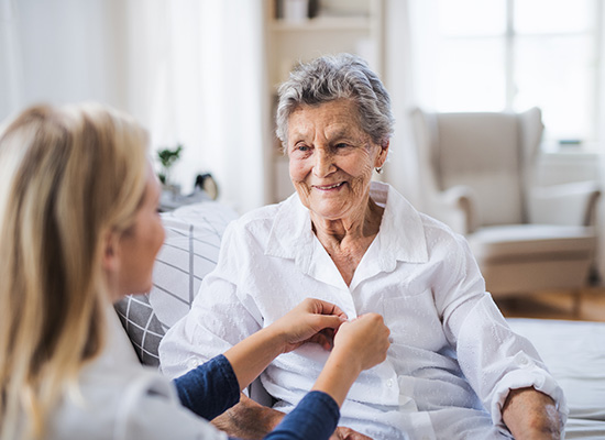 A caregiver helps an elderly woman, emphasizing the need for strong support systems and health care planning for childless or single seniors.