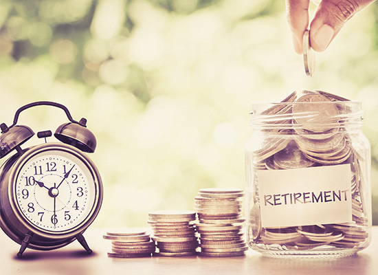 An alarm clock sits beside stacks of coins and a glass jar labeled 'RETIREMENT' being filled with money