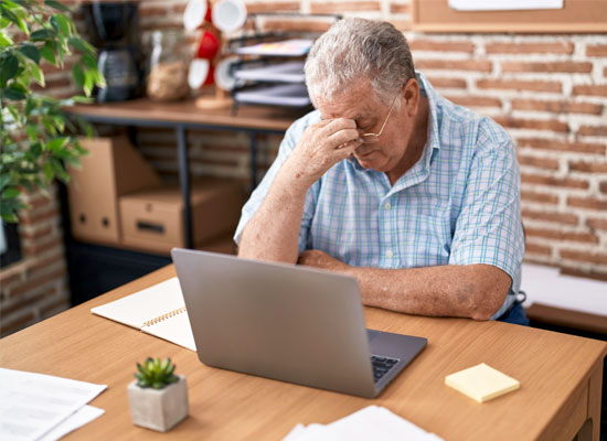 An older American worker experiences stress at his workplace, possibly facing age discrimination and employment challenges as he nears retirement.