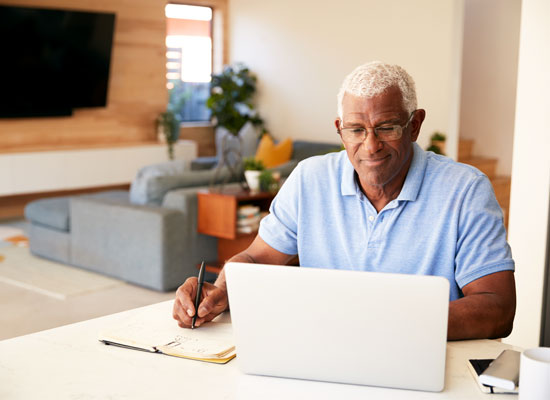 An older adult working on a laptop at home, focusing on retirement financial planning