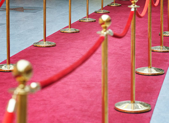A red carpet with gold stanchions symbolizes retirement-aged celebrities embracing post-retirement work, active retirement, and flexible career opportunities in their later years.