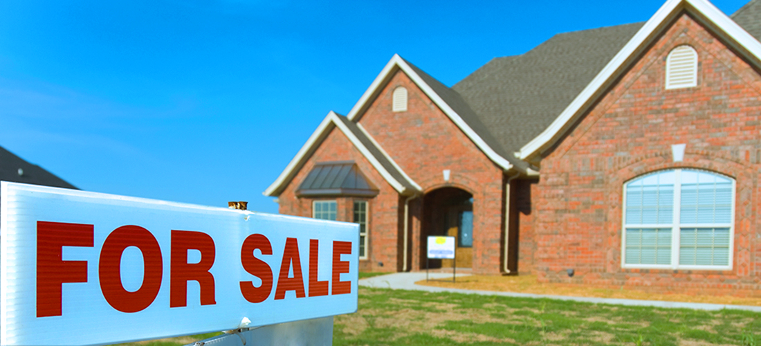 Large brick home with a for sale sign in the yard