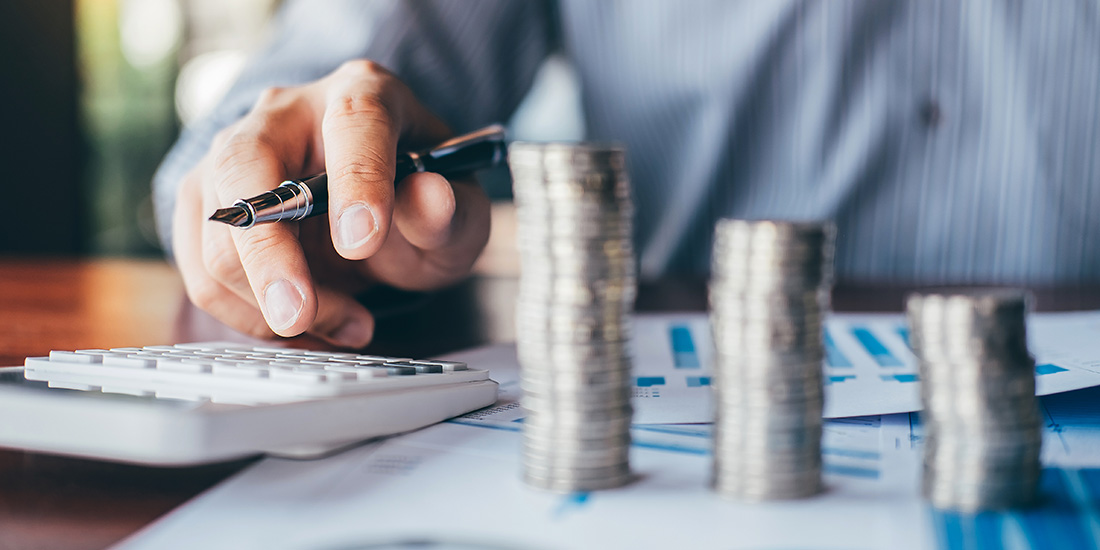Accountant calculating income tax with stacks of coins on desk