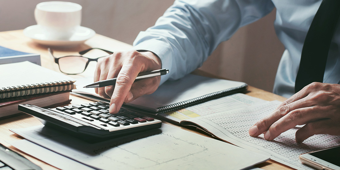 Accountant working at desk with calculator and cup of coffee