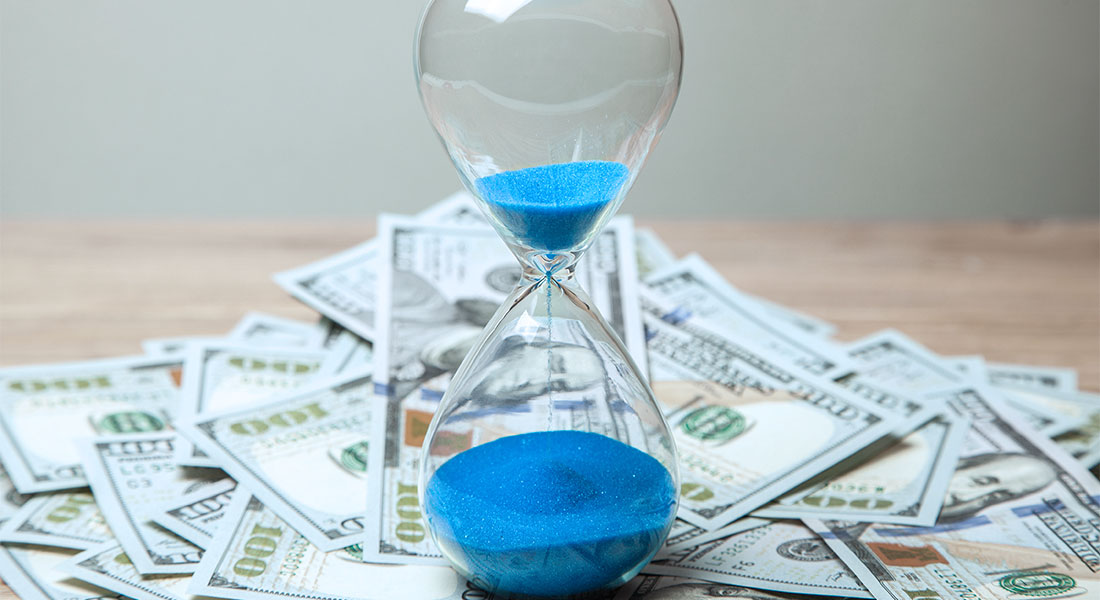Blue sand hour glass ontop of cash