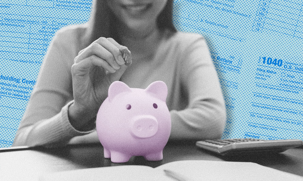 A person is placing a coin into a vibrant purple piggy bank atop a table, surrounded by tax documents and a calculator