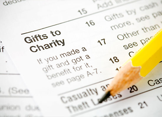 A close-up of a form titled 'Gifts to Charity' with a section numbered 16 to 20. A pencil rests on the page, emphasizing text about charitable donations and reporting them for tax deduction benefits