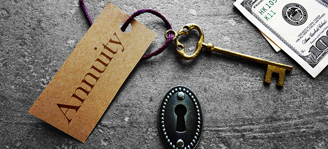 Old brass key with annuity label next to hundred dollar bill