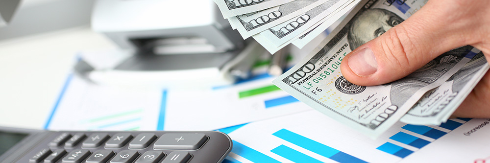 Man counting money at a desk with a calculator